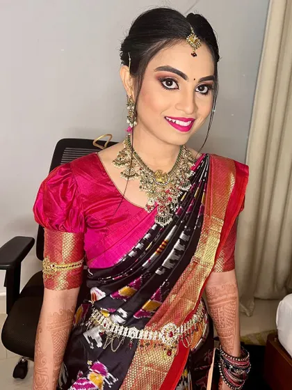 A smiling portrait of Bhanu. This angle shows off her elegant updo and the beautiful puff sleeves of her blouse, a modern twist on a traditional outfit.