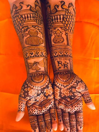 A personalized bridal mehendi featuring the couple's initials, the wedding date, and traditional motifs like peacocks and dhol drums.