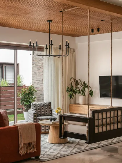 The informal living space features a traditional Indian swing, or 'jhoola', which adds a playful and rooted element. The room opens up to a garden, blurring the lines between indoors and outdoors.