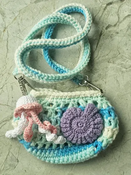 Another view of the mini Ocean Bag, showing the beautiful purple seashell appliqué and the jellyfish charm. The strap is detachable, so you can also use it as a small clutch.