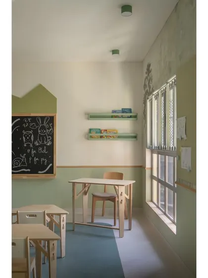 Every corner is a learning opportunity. This nook in the forest classroom features a teacher's desk, open shelving for books, and a uniquely shaped blackboard for lessons and doodles.