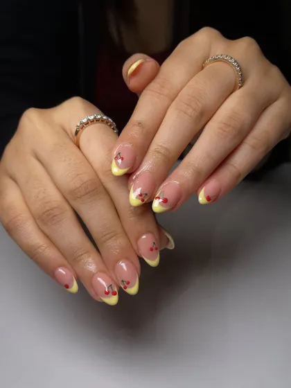 A playful twist on the French manicure. This set features cheerful yellow tips with tiny, hand-painted cherries for a fresh, summery vibe.
