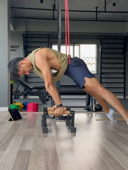 Working on a band-assisted planche on parallettes. This drill helps build the straight-arm and shoulder strength required for the full skill.