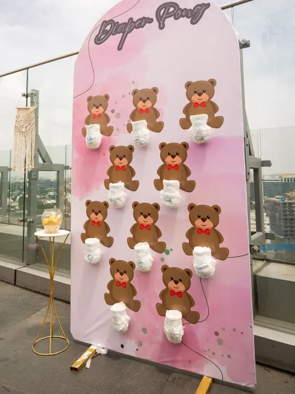 A "Diaper Pong" game set up on a rooftop for a boho baby shower. The pink backdrop and city view create a fun and unique setting for this classic baby shower game.
