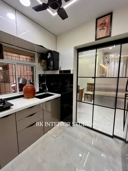 A view of the kitchen showing the fluted glass partition that connects to the dining area. This design allows for an open feel while still defining the kitchen space. You can also see the portrait of Babaji, a personal touch for the client.