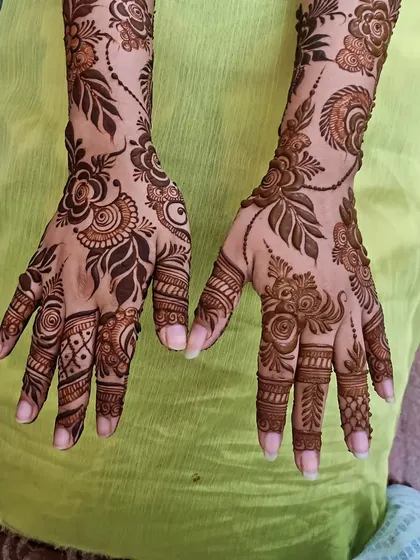 A full view of a floral henna design on both hands. The patterns are similar but not identical, giving a natural, hand-drawn feel.