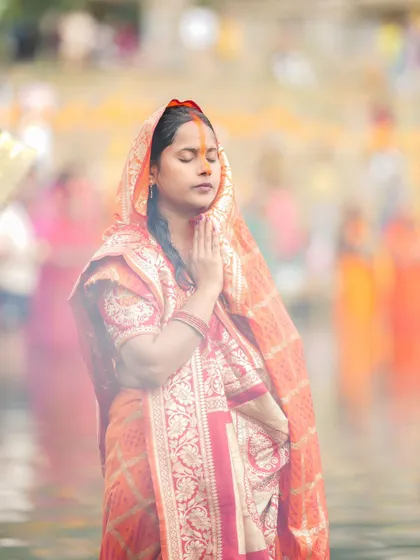 A woman in deep prayer during Chhath Puja, her eyes closed in concentration. It is a moment of profound connection with the life-giving energy of the sun.