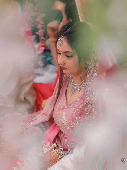 An artistic shot of the bride during the ceremony, framed by foreground elements to create a sense of depth and intimacy.
