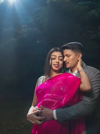 An intimate portrait of a couple near a waterfall, with dramatic backlighting creating a cinematic feel. This showcases our use of advanced lighting techniques in outdoor settings.