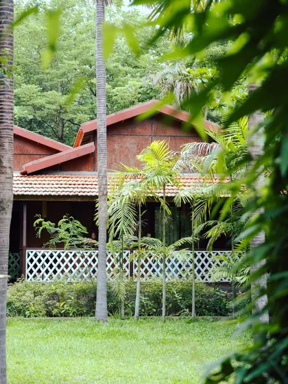 A view of our Kanakapura cottages, surrounded by tall trees and manicured lawns, promising a calm and peaceful retreat.