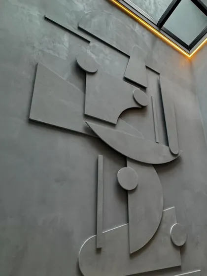 A custom-designed mural serves as the central art piece in this home. Crafted from microconcrete, the geometric shapes create a dynamic play of light and shadow, especially when illuminated by the skylight above.