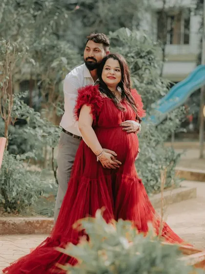 A sweet embrace captured during an outdoor shoot. The mom-to-be looks radiant in the ruffled red ball gown, perfect for celebrating this special time with a partner.