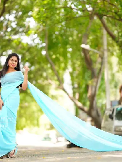 The full length of the sky-blue trail saree is captured in this wide shot.