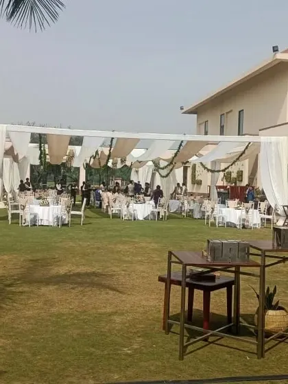 This shows a wide angle view of a large lawn party setup. You can see the main tented area for dining and high tables near the edge for a casual bar or cocktail section.