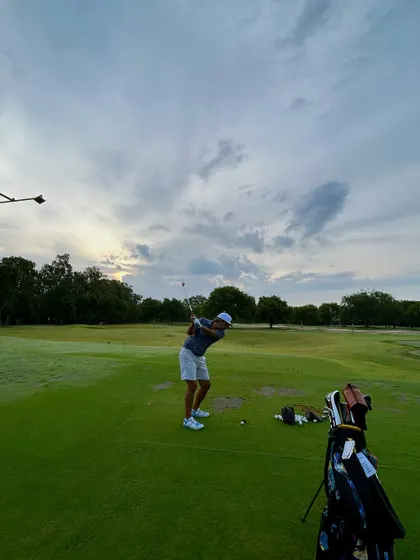 A beautiful shot of a golfer's follow-through against a dramatic, cloudy sky.