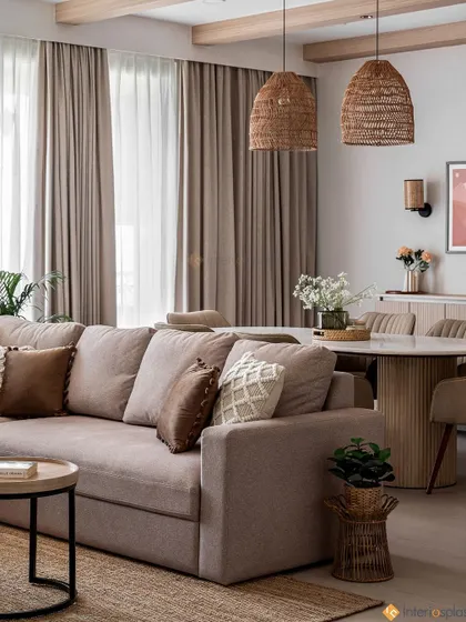 This living and dining area uses a soft, neutral color palette with natural textures like the woven pendant lights and jute rug. The layout creates a comfortable and cohesive space for relaxing and entertaining.