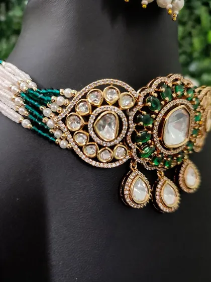 A close-up of a modern choker with large polki stones set against green beads. This rental piece is perfect for a contemporary and chic look.