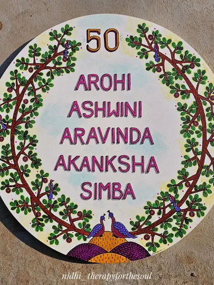 This large, 24-inch circular canvas was a custom souvenir for a 50th birthday. It features the family's names within a 'tree of life' border, painted in the traditional Gond art style.