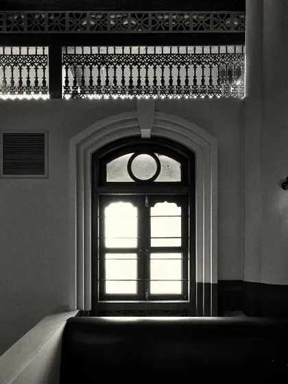 A similar arched window, framed by intricate decorative molding above. These details add to the historical, Calcutta-inspired theme.