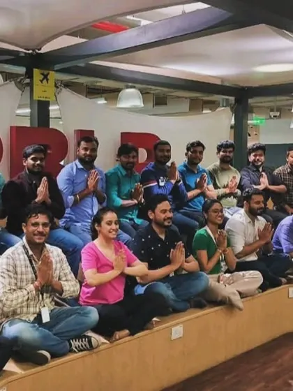 A wonderful group of employees at Delta Air Lines posing with 'Anjali Mudra' after a calming desk yoga session.