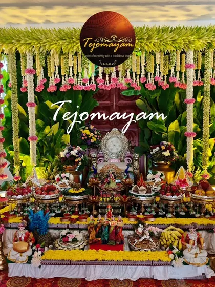 A half-saree ceremony setup with a backdrop of banana leaves and hanging floral garlands, complemented by a detailed arrangement of offering plates.
