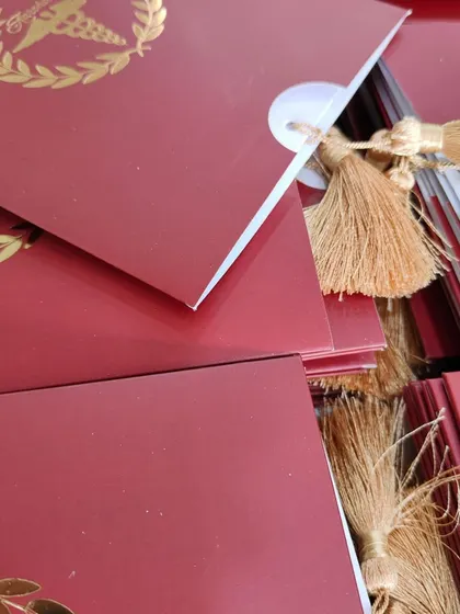 A close-up of the tassel and fan-folded insert for the graduation invitation, showing the fine details of the design.