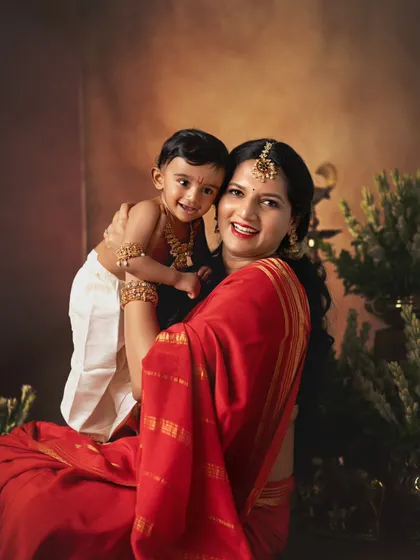 A classic Yashodha and Krishna portrait. The mother, dressed in a vibrant red saree, holds her little one, creating a powerful and loving image.