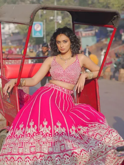 More than just fabric, this lehenga is woven with memories in mind. A model poses on a rickshaw in a vibrant pink lehenga, capturing the fun and festive spirit of an Indian wedding.