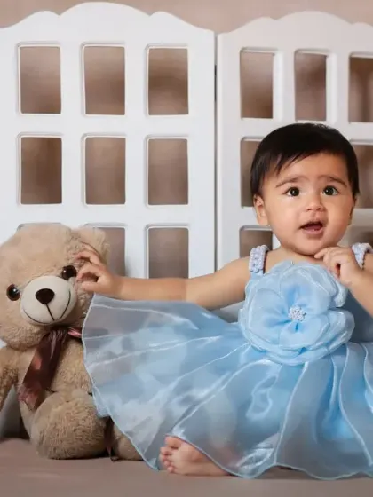 A sweet princess in a blue dress posing with her teddy bear friend in the boho setup.