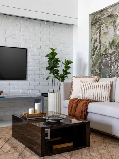 This angle shows the juxtaposition of the organic, jungle-themed wallpaper with a modern, white-painted brick wall. This contrast of textures adds depth and character to the eclectic living space.