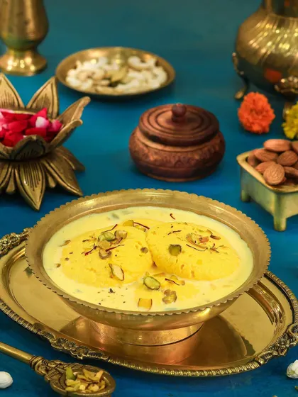 Rich and creamy Rasmalai in a traditional brass bowl, garnished with pistachios and saffron for a truly royal look.