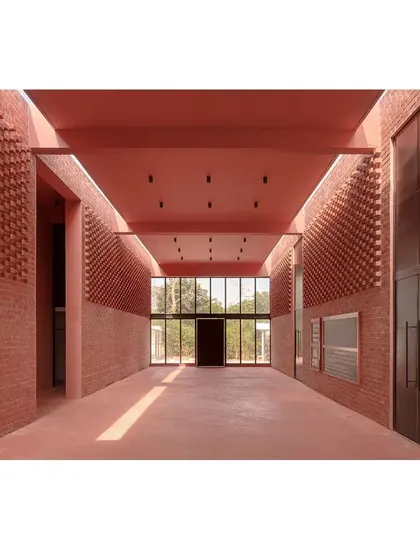 A wide shot of the main hall, showing the interplay between the solid brick walls and the open, glazed facade. The design balances enclosure with a connection to the outdoors.