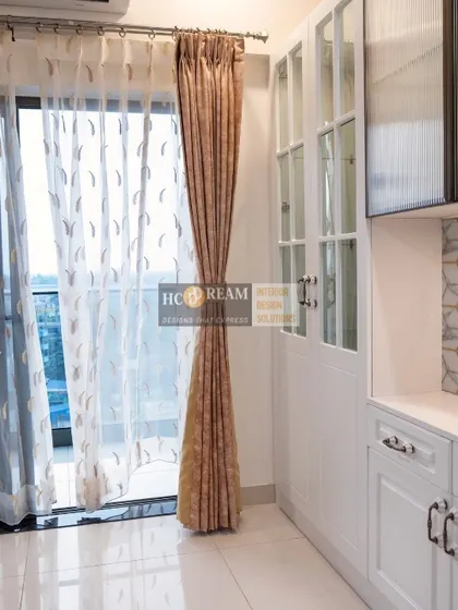A beautiful detail from the Kolkata project, showing the elegant white cabinetry with classic handles and a view to the balcony with sheer curtains.