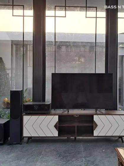 This entertainment den features Monitor Audio Bronze tower speakers and a subwoofer, creating a powerful soundstage for both movies and music. The system is designed to complement the modern interior of the glass-enclosed space.