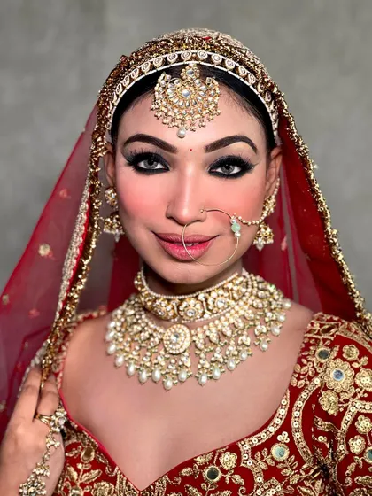 A smiling bride, radiating happiness in our classic red bridal lehenga. The pearl-drop kundan necklace is a perfect match.
