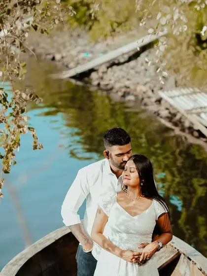 A beautiful portrait of the couple in a boat, framed by overhanging branches, creating a natural and intimate setting.