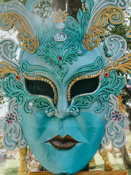 An oversized, ornate masquerade mask in shades of blue and gold, serving as a stunning and artistic decor piece for the festival-themed event.