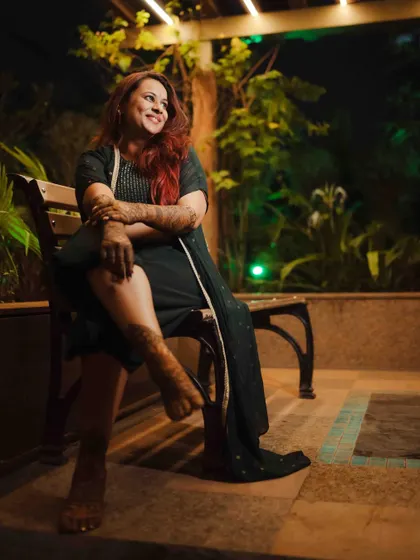 A relaxed and happy portrait of the bride on a bench, her henna-covered legs crossed, enjoying the evening.