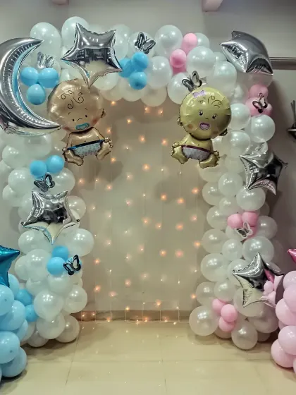 A sweet 'Twinkle Twinkle Little Star' theme for a baby shower. This setup features a balloon arch in white, pink, and blue, with silver moon and star foil balloons and cute baby characters.
