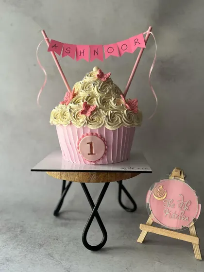 A fun twist on a first birthday cake, this giant cupcake is big enough for everyone to share. It's decorated with pink buttercream and a custom name banner.