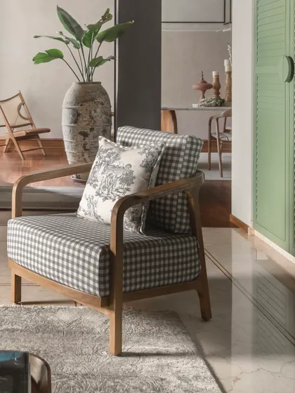 A beautiful checkered armchair with a toile-patterned cushion, set against a backdrop of a large rustic vase and a mint green cabinet. This composition is a reminder that contrast doesn’t clash when there’s a clear story.
