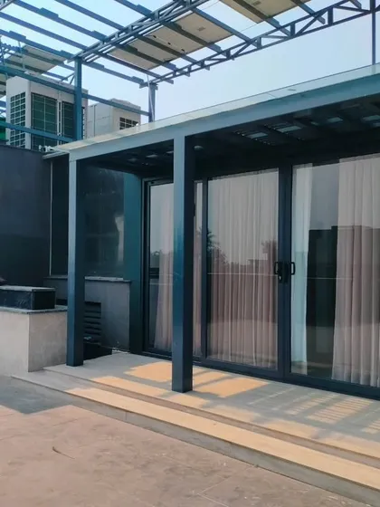 A completed porta-cabin structure on a rooftop, featuring large sliding glass doors and an attached pergola.