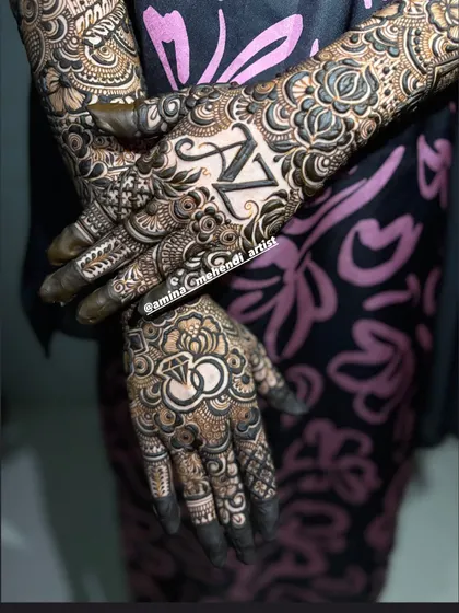 A detailed shot of the 'AZ' engagement mehendi, highlighting the fine line work and shading in the rose patterns that complement the personalized initials.