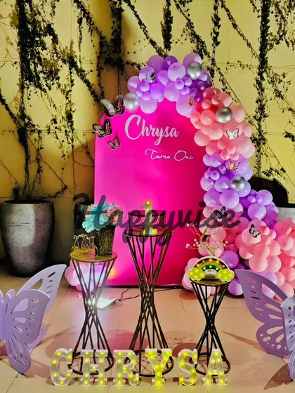 "Wings of whimsy" for Chrysa's first birthday. This butterfly-themed setup uses a bold pink backdrop and large purple butterfly cutouts for a modern and stylish look.