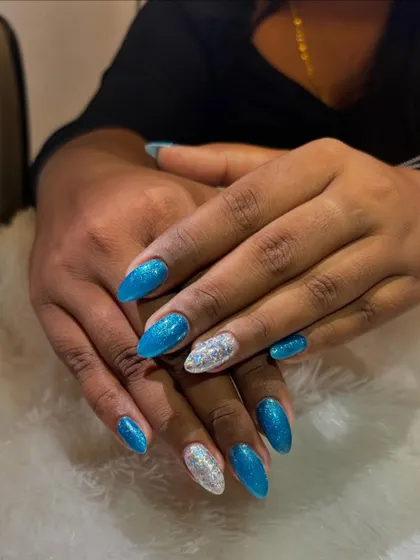This frozen-inspired look combines sparkling turquoise glitter nails with a brilliant silver glitter accent nail. The almond shape and icy colors create a glamorous and magical wintery vibe.