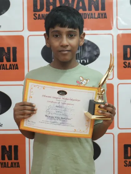 A young boy proudly holds his certificate and trophy.