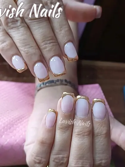 An elegant French manicure with a twist, featuring a metallic gold tip on short, square nails for a touch of luxury.