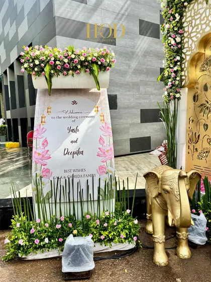 A personalized welcome sign for the couple, Yash and Deepika, adorned with lotus illustrations and flanked by a golden elephant statue.