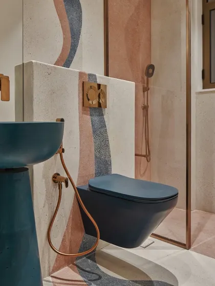 The kids' bathroom is where we really had fun with color. A bold blue pedestal basin and matching WC are set against a terrazzo-style wall with flowing patterns of orange and blue, creating a vibrant and energetic space.