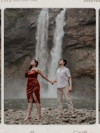 A powerful and romantic shot of the couple standing hand-in-hand in front of the waterfall.